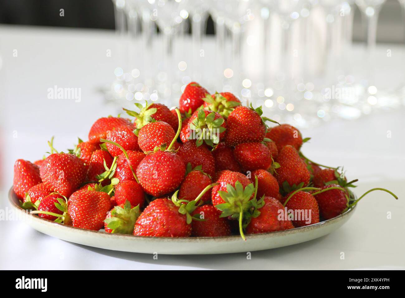 Fraises dans une assiette sur une nappe blanche. Fraises dans une assiette ronde sur une table blanche. Fraises magnifiques mûres et sucrées dans une assiette sur un wh Banque D'Images