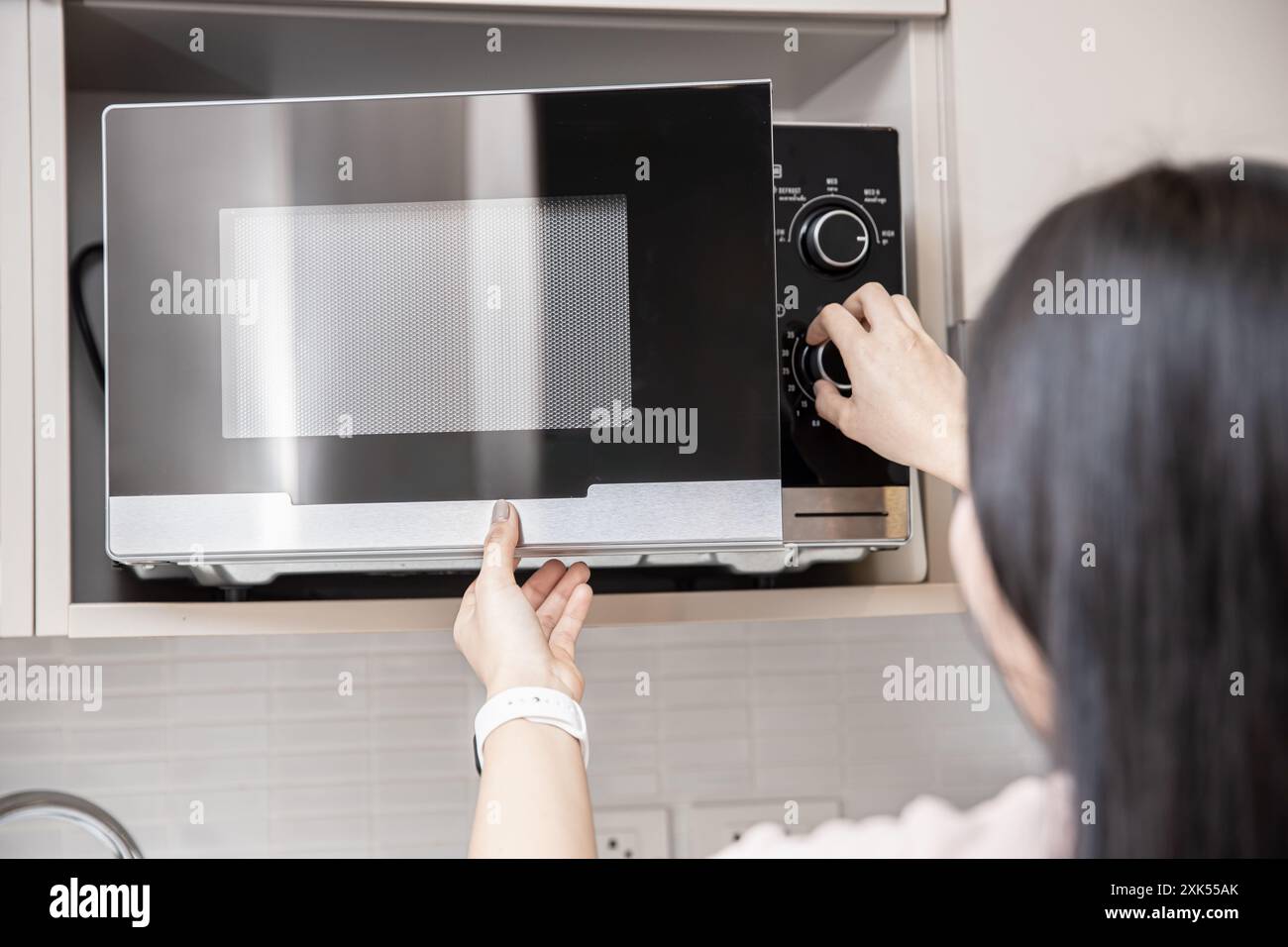 les personnes utilisant le four à micro-ondes, les femmes ajustent le temps pour réchauffer les aliments chauds au micro-ondes. Banque D'Images