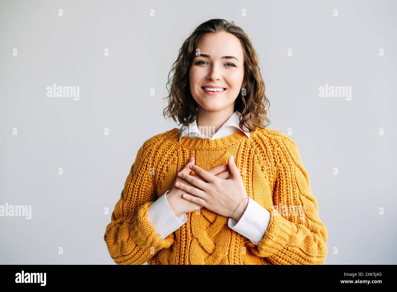 Reconnaissante jeune femme exprimant la gentillesse. Une jeune femme heureuse avec les mains sur la poitrine, montrant gratitude et gentillesse. fond blanc, rayonnant Banque D'Images