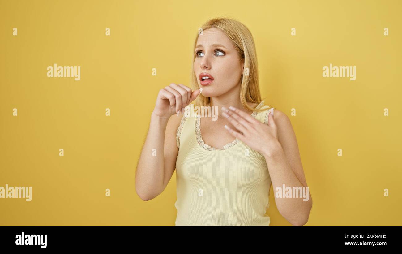 Jeune femme blonde toussant sur un fond jaune isolé, montrant des signes d'inconfort. Banque D'Images