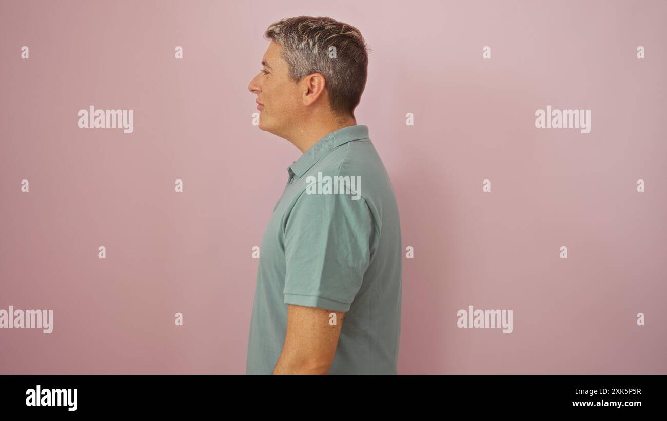 Bel homme dans la vue de profil sur un fond rose portant une chemise verte décontractée Banque D'Images