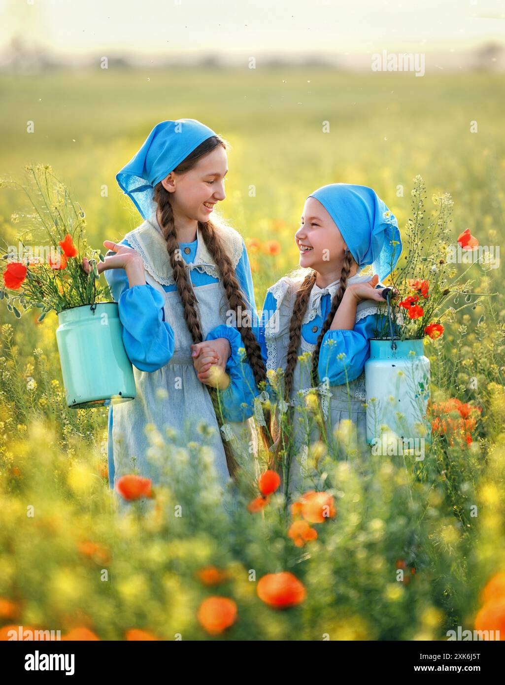 Soeurs. Portrait d'enfants mignons filles dans le champ de pavot. Enfants en robe bleue heureux avec bouquet de coquelicots au coucher du soleil d'été Banque D'Images