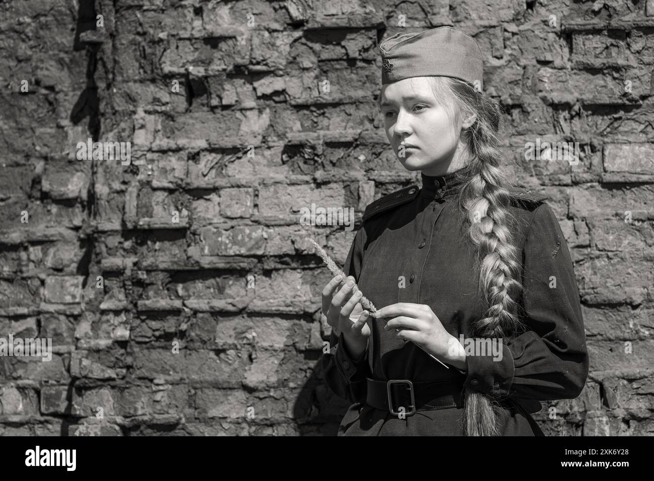 Une infirmière de première ligne en uniforme de l'Armée rouge de la seconde Guerre mondiale pleure contre un mur de briques. Banque D'Images