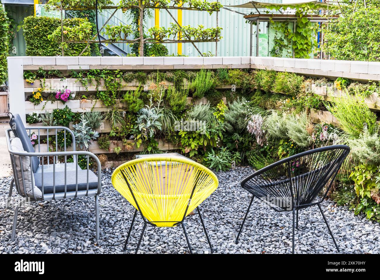 Chaises de jardin dans un coin salon avec parterres de fleurs verticaux Banque D'Images