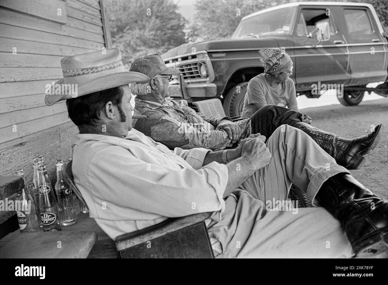 Macédoine, Arkansas, États-Unis – 27 juin 2024 : photo horizontale de trois amis assis devant un vieux magasin de campagne. Banque D'Images