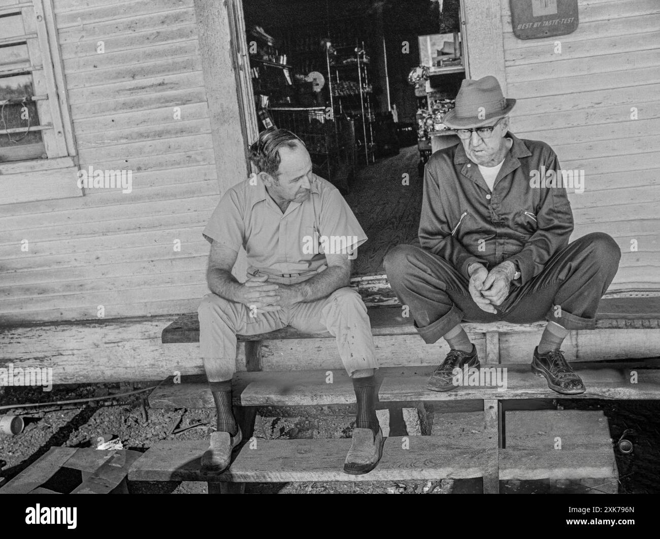 Macédoine, Arkansas, États-Unis – 27 juin 2024 : photo horizontale de deux vieux amis assis à l'extérieur sur les marches d'un vieux magasin de campagne. Banque D'Images