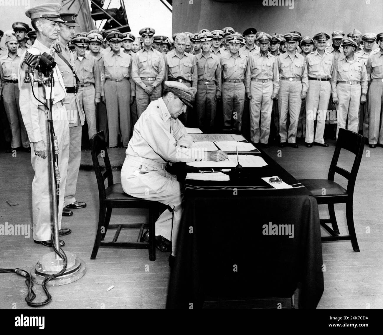 Le général américain Douglas MacArthur assis à son bureau lors des cérémonies officielles de reddition à bord de l'USS Missouri alors que les soldats regardent, Tokyo Bay, Japon, U.S. Army signal corps, 2 septembre 1945 Banque D'Images