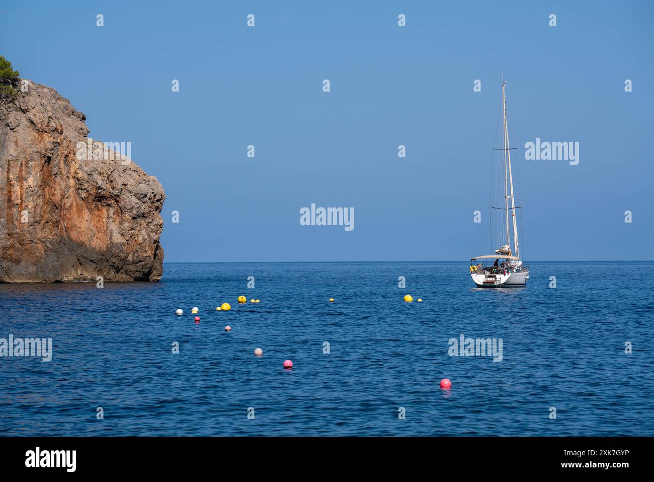 En face du cap il y a un yacht solitaire ; il y a beaucoup de bouées colorées dans la mer. Journée ensoleillée, mer transparente bleue. Île de Majorque, îles Baléares Banque D'Images