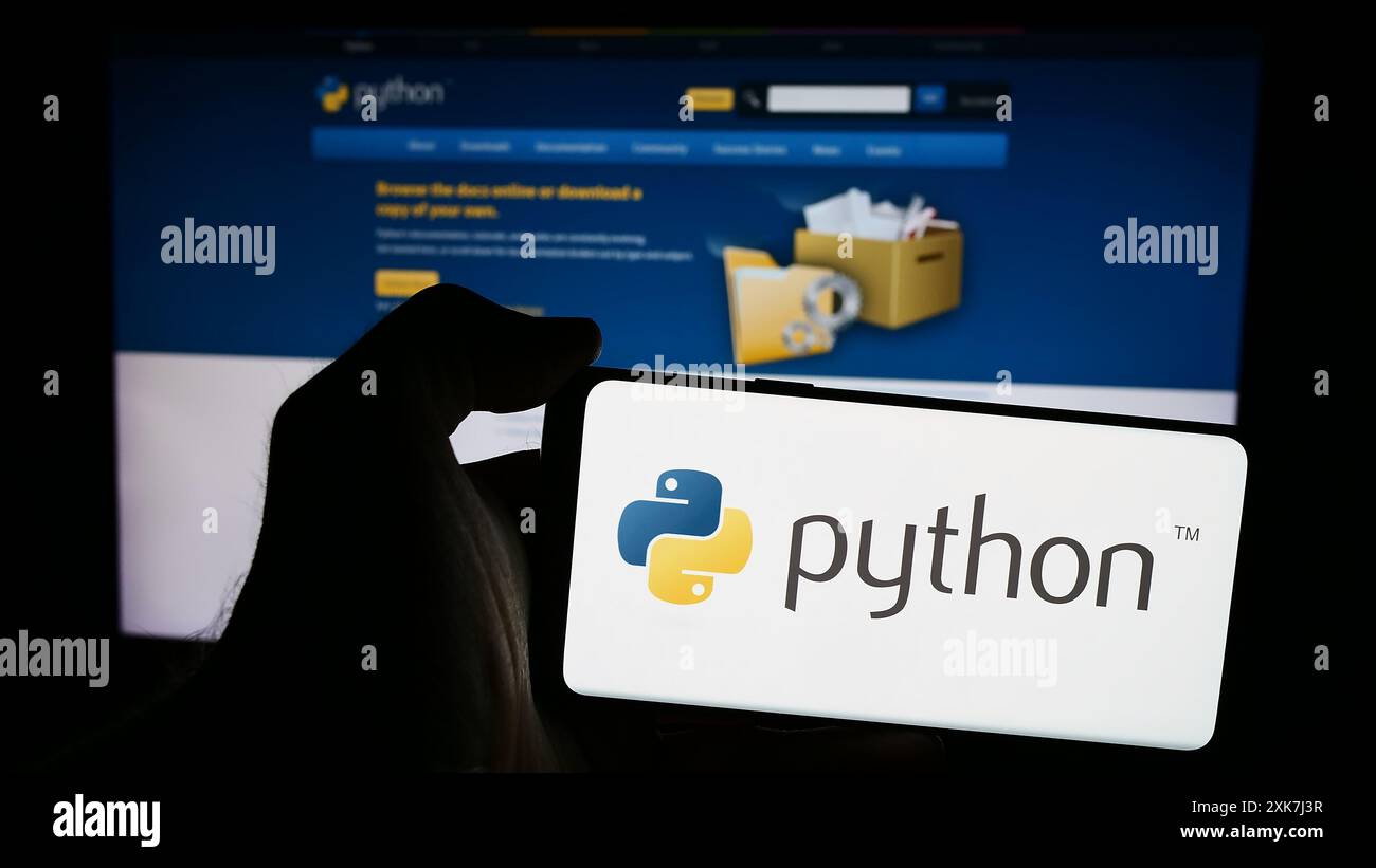 Personne tenant le téléphone portable avec le logo de l'organisation Python Software Foundation (PSF) devant la page Web. Concentrez-vous sur l'affichage du téléphone. Banque D'Images