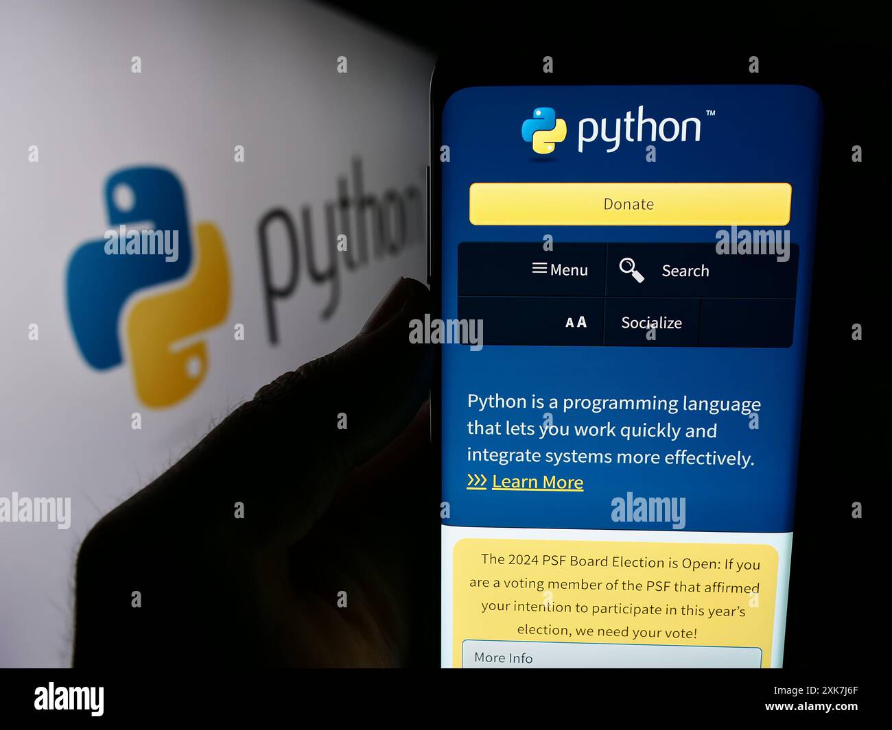 Personne tenant le téléphone portable avec le site Web de l'organisation Python Software Foundation (PSF) devant le logo. Concentrez-vous sur le centre de l'écran du téléphone. Banque D'Images