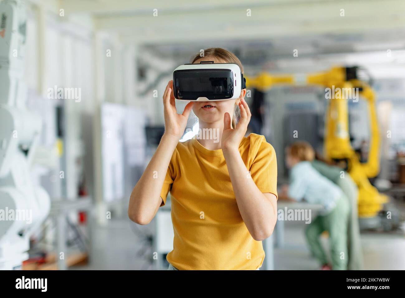 Portrait d'écolière avec casque VR sur la tête. Enfants apprenant la robotique à l'école primaire, en utilisant la technologie moderne, la réalité virtuelle. Banque D'Images