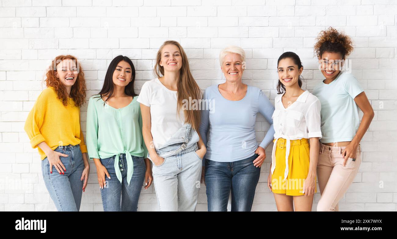 Diverses femmes de différentes âges se tenant sur le mur blanc de brique Banque D'Images