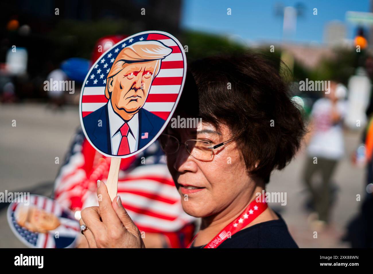 MILWAUKEE, WISCONSIN - 17 JUILLET : une femme tient un fan avec une image de l'ancien président Donald J Trump devant FinServ Forum le premier jour de la Convention nationale républicaine (RNC) le 17 juillet 2024, à Milwaukee, Wisconsin. La convention se déroule comme prévu malgré la tentative d'assassinat contre Trump qui se conclura par son acceptation de la nomination présidentielle de son parti. Banque D'Images