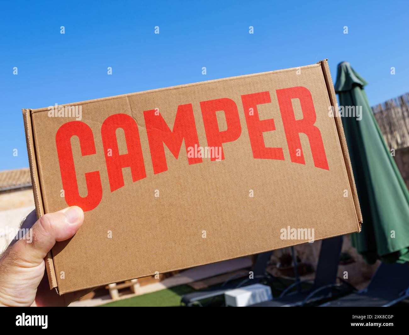 Palma, Espagne - 11 juillet 2024 : une main masculine tient une boîte en carton d'appareil photo contre un ciel bleu clair, offrant une perspective de point de vue de l'emballage dans un cadre ouvert et ensoleillé Banque D'Images