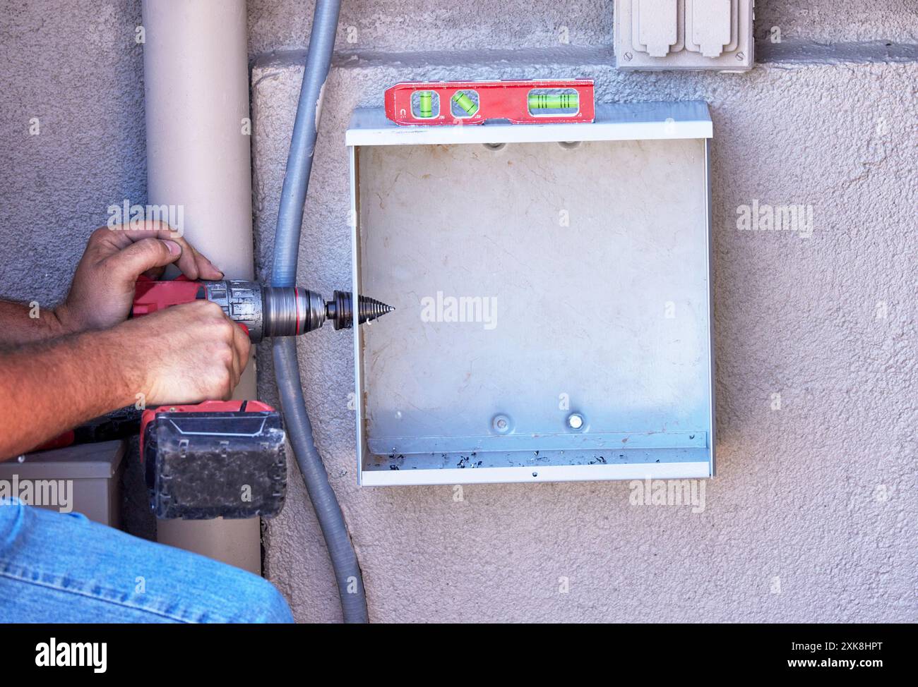 Mains d'un électricien installant une boîte J. Banque D'Images