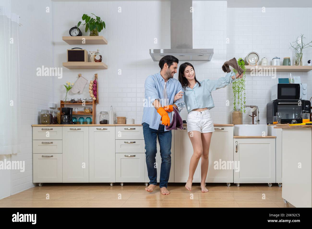 Concept de nettoyage. Joyeuse jeune femme européenne et masculine lavant la vaisselle dans l'intérieur de la cuisine moderne. Hygiène, tâches ménagères dans le temps libre. Jeune fami Banque D'Images