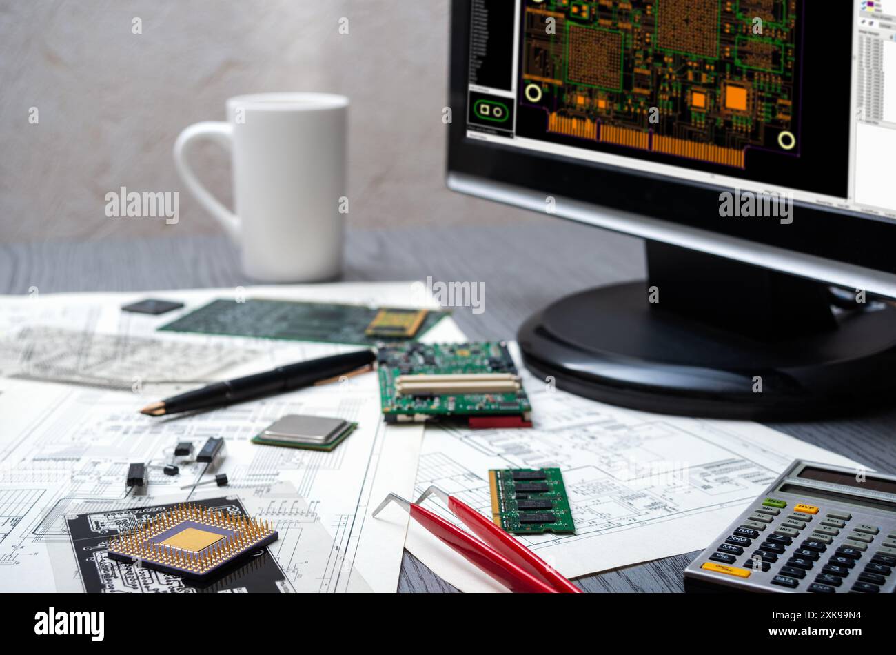 Espace de travail d'ingénierie électronique avec écran d'ordinateur affichant une conception de carte de circuit imprimé, des composants et des outils sur un bureau. Banque D'Images