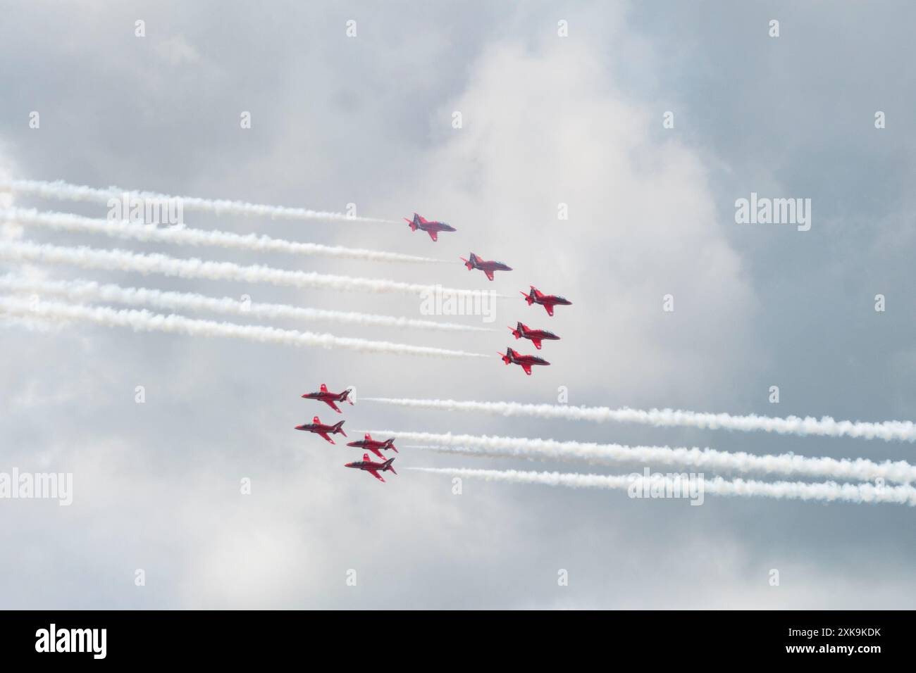 Neuf flèches rouges britanniques, divisées en quatre et cinq, croisent dans le ciel avec des traînées de fumée blanche. Prise au Grand Prix de Silverstone 2024 Banque D'Images