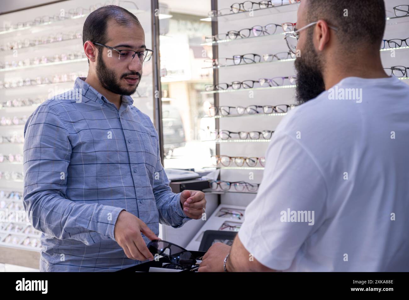 Masculin sélectionnant les meilleures lunettes, sélectionnant également des lunettes de soleil whihc est clips lunettes Banque D'Images