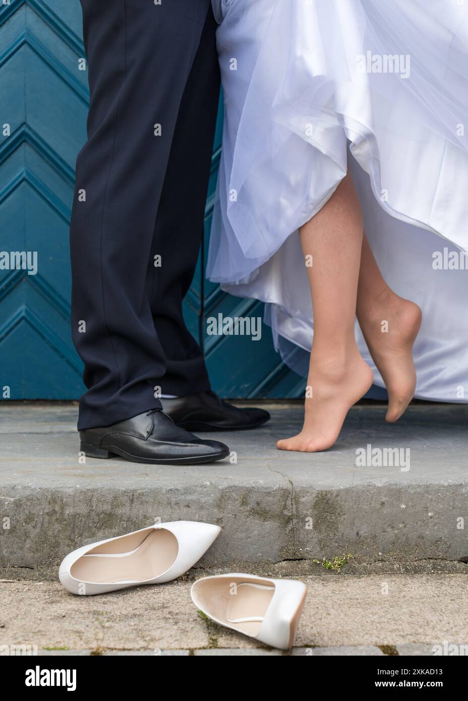 Détails du mariage. Un couple de mariage sur un fond de portes bleues. Seuls les pieds du jeune couple, la mariée se tient sans chaussures, chaussures de mariage Banque D'Images