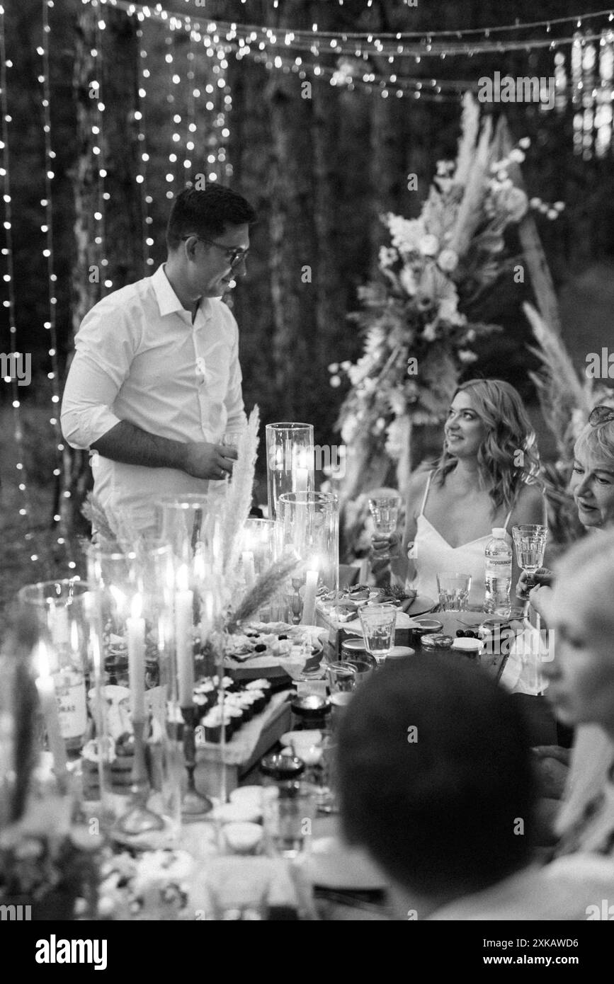 dîner de mariage en famille dans la forêt avec des ampoules et des bougies Banque D'Images