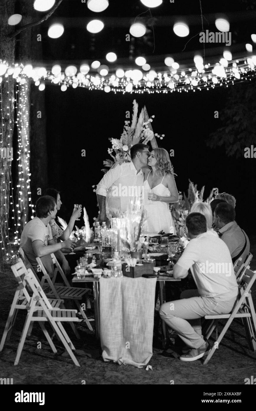 dîner de mariage en famille dans la forêt avec des ampoules et des bougies Banque D'Images