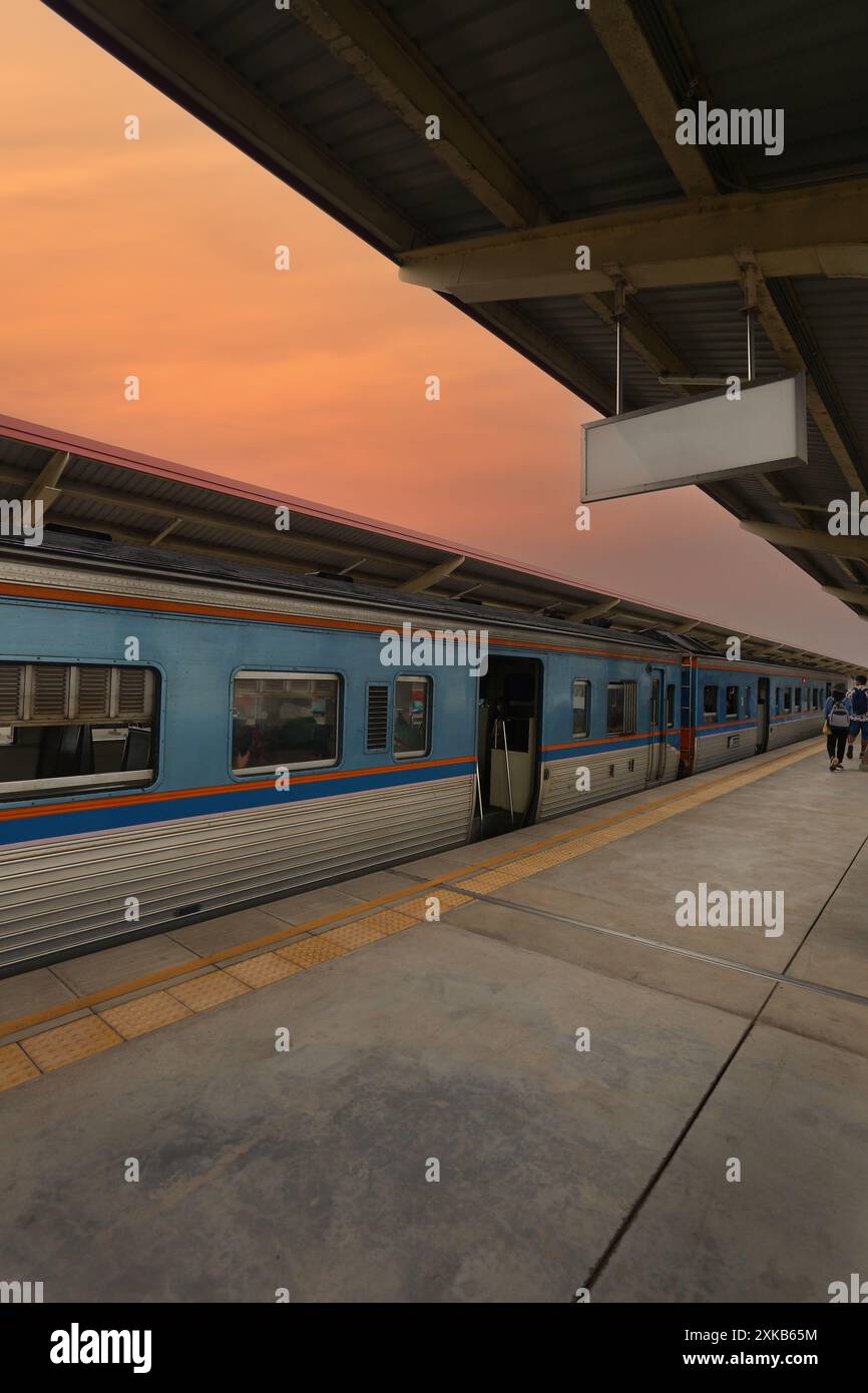 Gare au crépuscule avec des trains stationnés et un panneau blanc suspendu pour votre conception. Banque D'Images