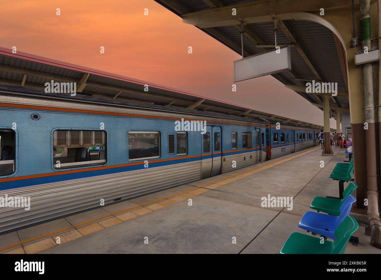 Gare au crépuscule avec des trains stationnés et un panneau blanc suspendu pour votre conception. Banque D'Images