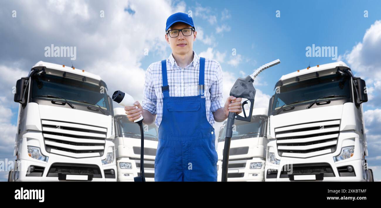 Un homme portant un uniforme de conducteur bleu tient la prise de charge et la buse de ravitaillement du véhicule électrique sur un fond de camions. Concept de comparaison énergétique.. Banque D'Images