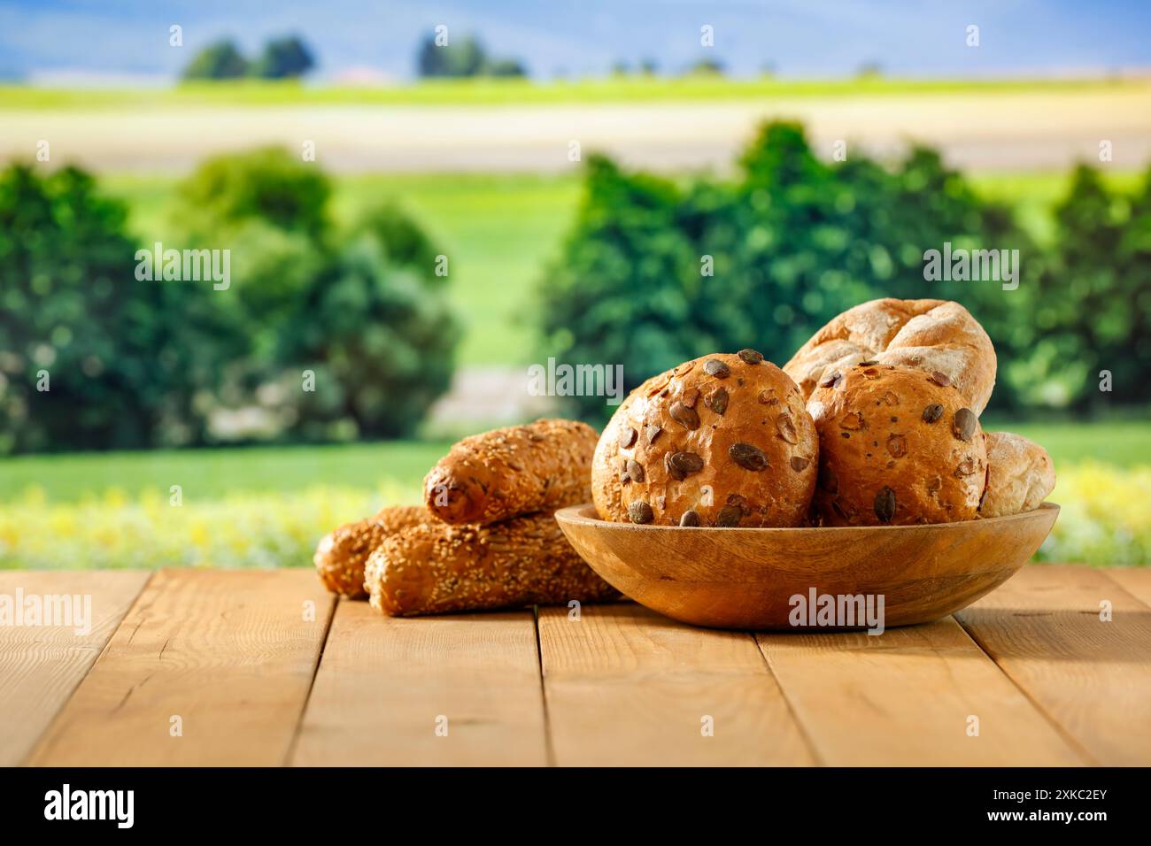 Pain frais cuit au four, petits pains sur la table en bois. Fond de champ vert. Copier l'espace pour les produits. Concept de campagne. Image pour l'affichage du montage des produits. Banque D'Images