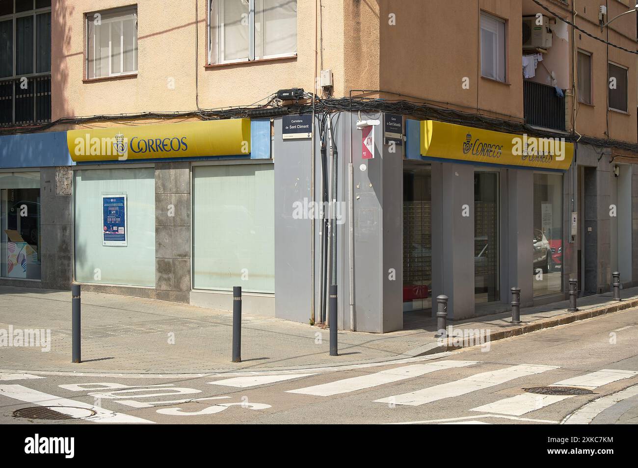 Viladecasn, ESPAGNE - 22 JUILLET 2024 : image d'un bureau de poste situé à l'angle d'une rue urbaine. Le bâtiment a des fenêtres en verre dépoli et un YE Banque D'Images