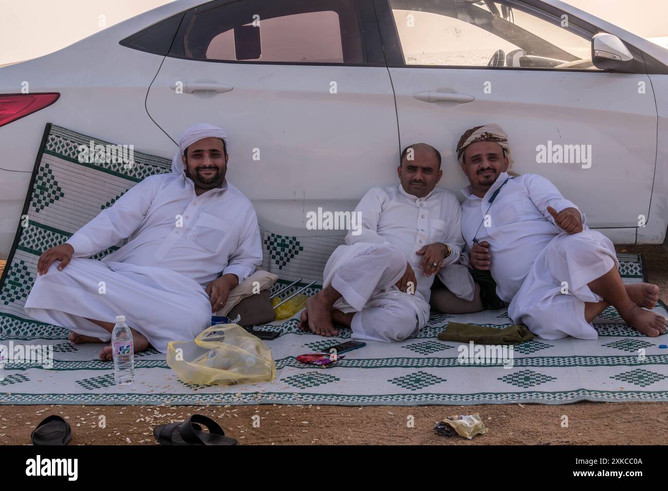 Trois Arabes musulmans pique-niquent près de la voiture à Djeddah, Arabie Saoudite. Banque D'Images