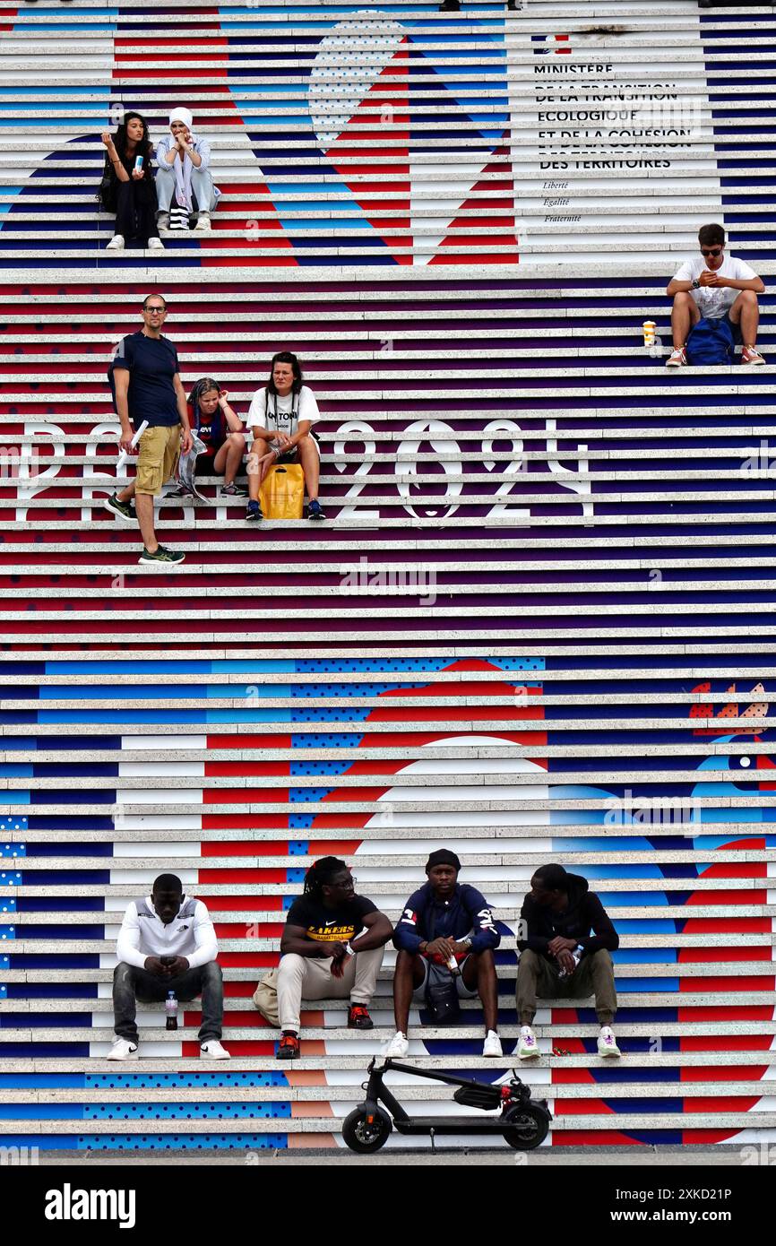 Paris, France. 22 juillet 2024. Les gens sont assis sur les marches de l'Arc de la Défense décoré des signes olympiques Paris 2024 à Paris, France, le 22 juillet 2024. La cérémonie d'ouverture a lieu le 26 juillet, 100 ans après la dernière fois que Paris a accueilli les jeux. Photo de Richard Ellis/UPI crédit : UPI/Alamy Live News Banque D'Images