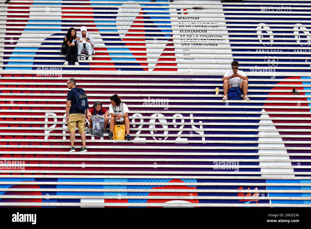 Paris, France. 22 juillet 2024. Les gens sont assis sur les marches de l'Arc de la Défense décoré des signes olympiques Paris 2024 à Paris, France, le 22 juillet 2024. La cérémonie d'ouverture a lieu le 26 juillet, 100 ans après la dernière fois que Paris a accueilli les jeux. Photo de Richard Ellis/UPI crédit : UPI/Alamy Live News Banque D'Images