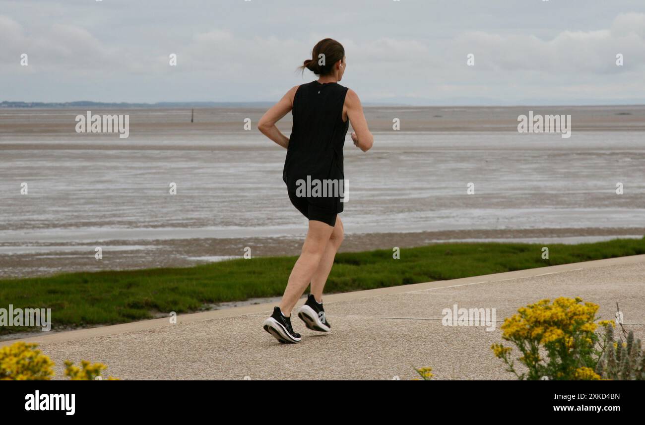 Une dame qui court sur le front de mer Banque D'Images