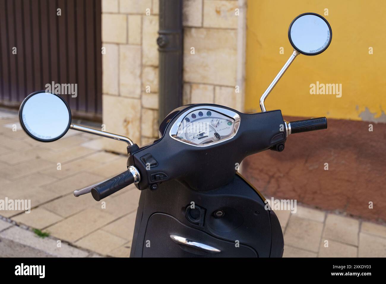 Astorga, Espagne - 4 juin 2023 : un scooter noir est garé sur un trottoir dans une ville européenne, baigné par la lumière chaude du soleil, avec ses miroirs reflétant le th Banque D'Images