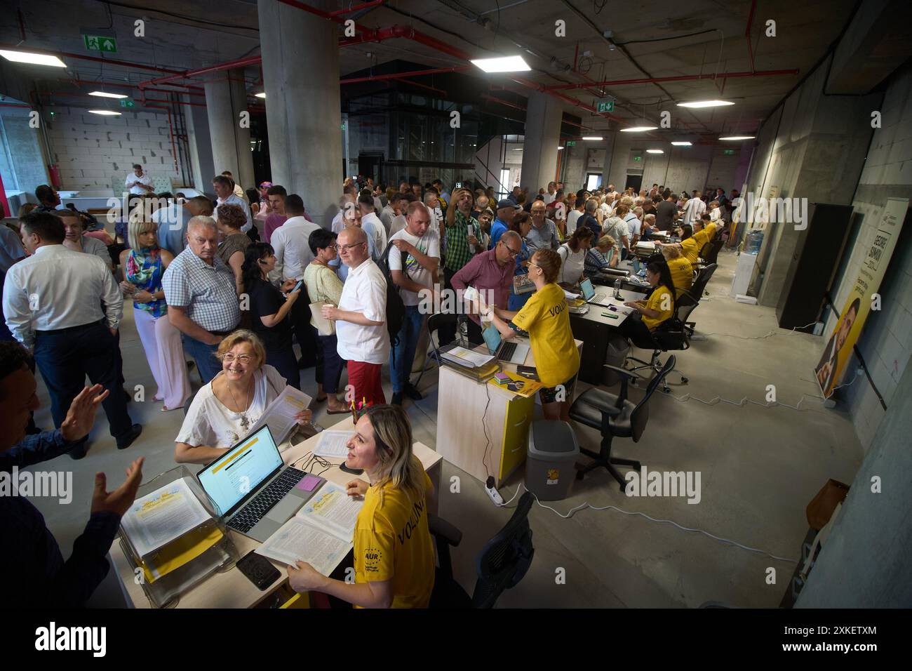 Bucarest, Roumanie. 22 juillet 2024 : des volontaires aident les gens à remplir 'le contrat d'inscription au plan Simion', lors d'une action de campagne présidentielle de George Simion, le candidat du parti populiste et nationaliste de droite Aur (Alliance pour l'Union des Roumains), à son siège de campagne dans le magasin de Bucarest. « Le plan Simion » vise à faciliter l’achat sans intérêt d’un appartement à partir de 35 000 euros et le refinancement, sans intérêt et autres coûts entièrement subventionnés par l’Etat, des prêts hypothécaires existants entre 35 000 et 70 000 euros. Crédit : Lucian Banque D'Images