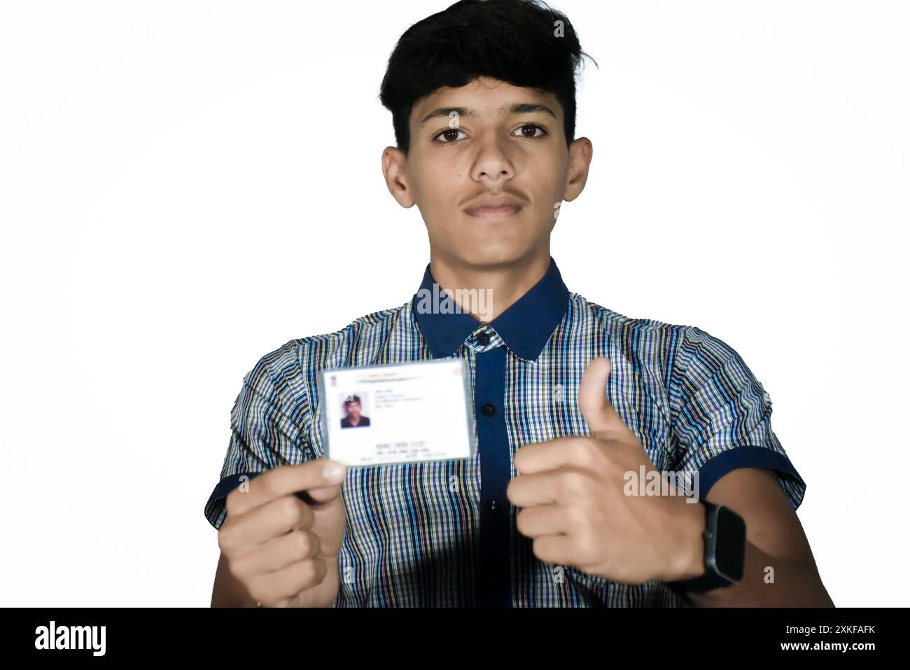 Écolier indien portant l'uniforme bleu foncé de l'école, montre la carte aadhar floue hir dans sa main. Banque D'Images