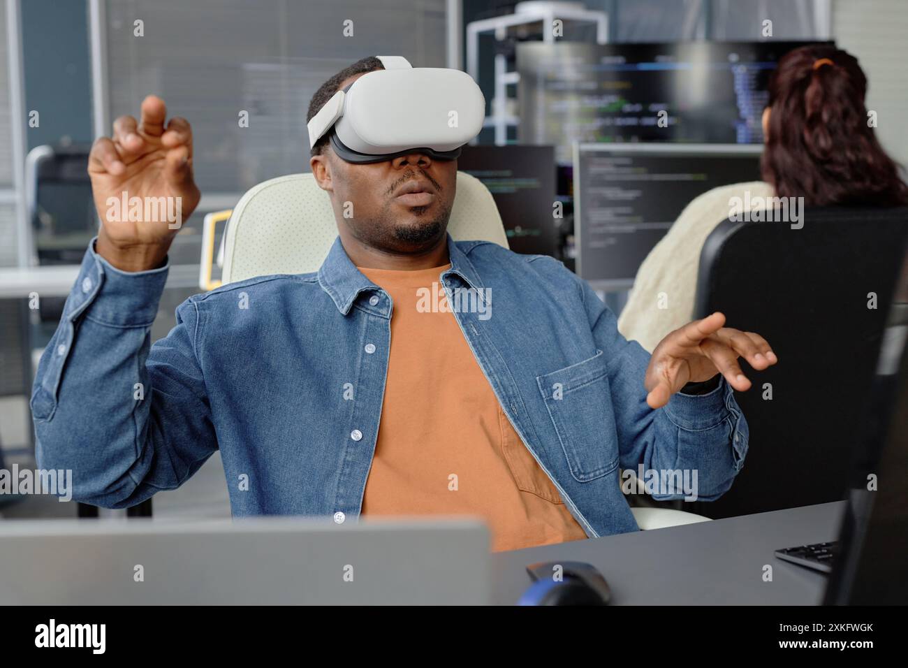 Développeur de logiciels afro-américain masculin testant l'application VR ou le jeu portant un casque entièrement immergé dans l'expérience de bureau virtuel Banque D'Images