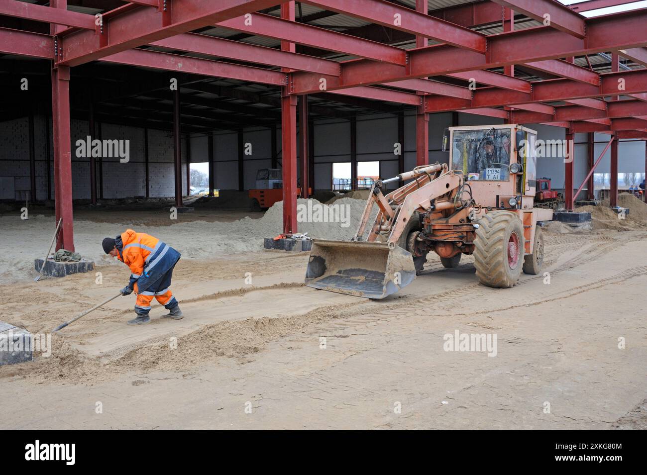 Construction du hangar. Bulldozer travaillant, homme ouvrier creusant avec une pelle. 20 mars 2019. Berezovka, Ukraine Banque D'Images