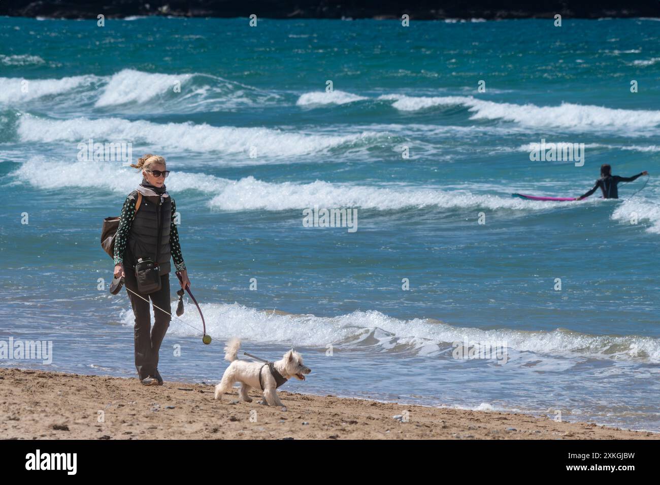 Une femme mûre promenant son chien de compagnie le long de la plage de Fistral Beach, à Newquay en Cornouailles, au Royaume-Uni. Banque D'Images