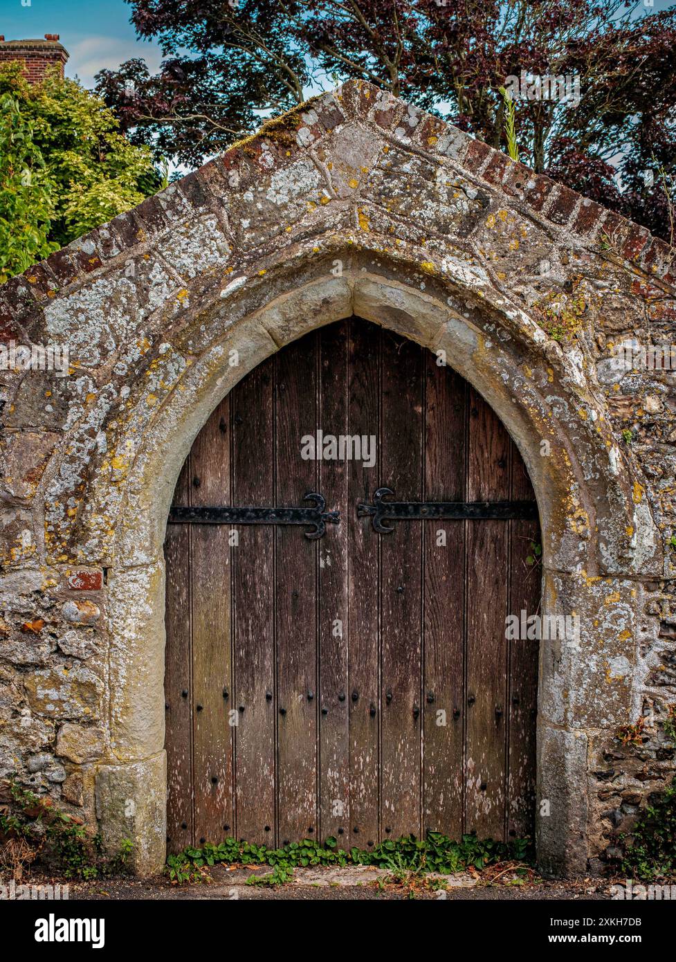 Vieille double porte en bois dans le mur de pierre à Bosham, West Sussex, Royaume-Uni Banque D'Images