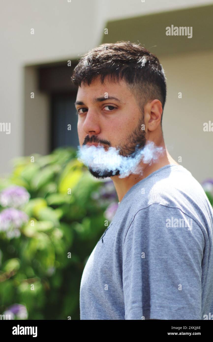 Une image vivante montrant un jeune homme fumant un joint par une journée ensoleillée dans la ville de Zurich. Idéal pour les thèmes liés à la culture urbaine, la détente, et l Banque D'Images