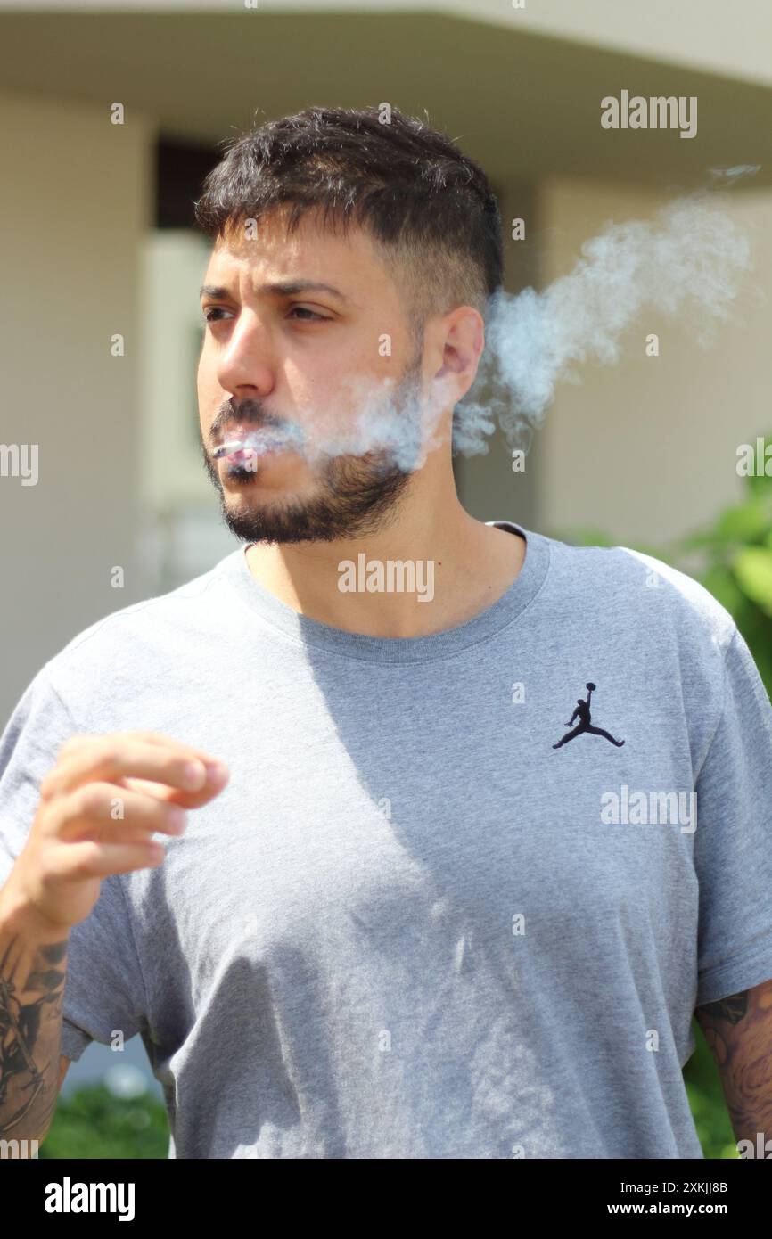 Une image vivante montrant un jeune homme fumant un joint par une journée ensoleillée dans la ville de Zurich. Idéal pour les thèmes liés à la culture urbaine, la détente, et l Banque D'Images
