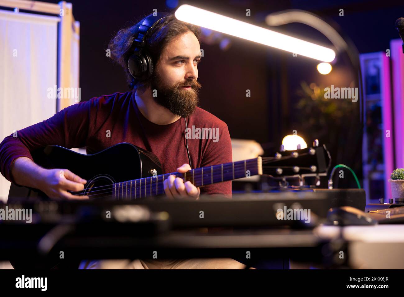 Artiste musical mixant et masterisant des airs de guitare joués sur un instrument acoustique, en utilisant des commandes électroniques sur la console et le logiciel daw. Auteur-compositeur producteur créant de nouveaux sons, home studio. Banque D'Images