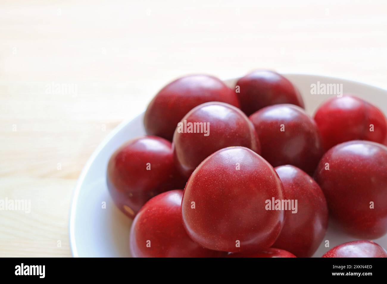 Tas de fruits frais de prune de rubis du golfe nain dans une assiette blanche Banque D'Images