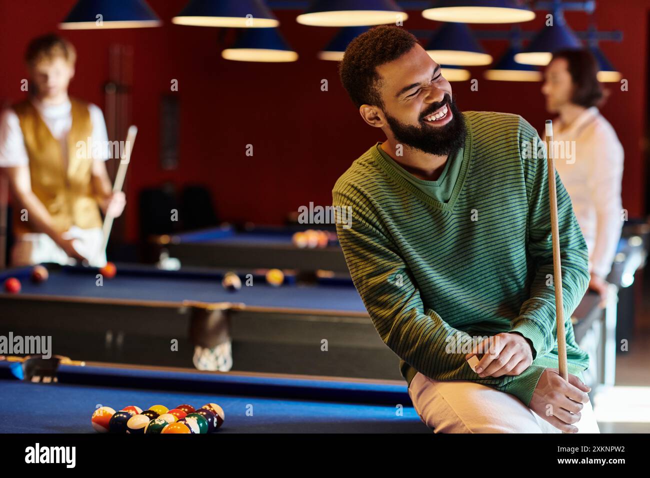 Les amis profitent d'une partie de billard décontractée ensemble dans un bar faiblement éclairé. Banque D'Images