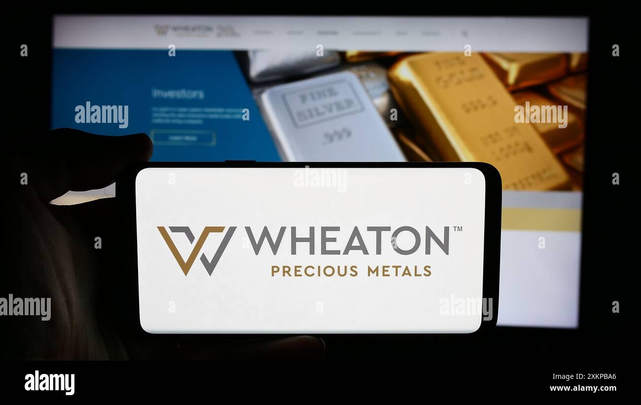 Personne tenant un téléphone portable avec le logo de la société canadienne de métaux Wheaton Precious Metals Corp. devant la page Web de l'entreprise. Concentrez-vous sur l'affichage du téléphone. Banque D'Images