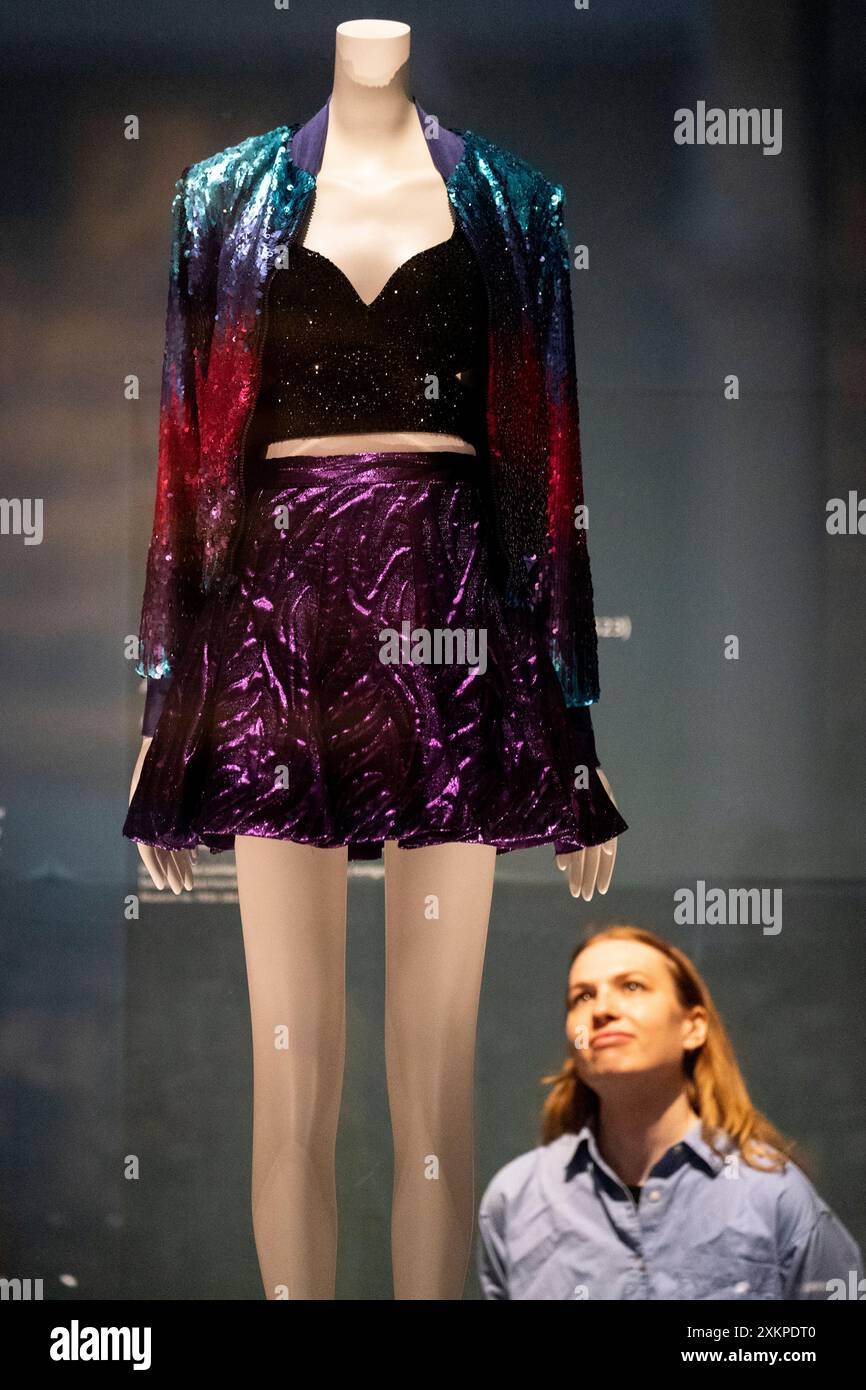 Un assistant de galerie regarde une tenue portée par Taylor Swift lors de la tournée mondiale 1989 lors d'une visite photo pour le Taylor Swift Songbook Trail, au Victoria and Albert Museum (V&A) à South Kensington, Londres. Le sentier temporaire gratuit comprend 13 installations qui célèbrent le processus créatif et la carrière de Taylor Swift, artiste primé 14 fois aux Grammy Awards. Date de la photo : mercredi 24 juillet 2024. Banque D'Images