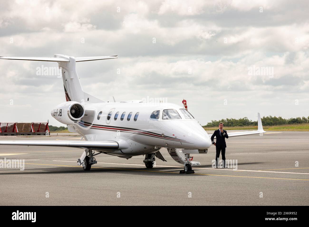 Pilote NETJETS debout à côté d'un jet Embraer Phenom 300E. Banque D'Images